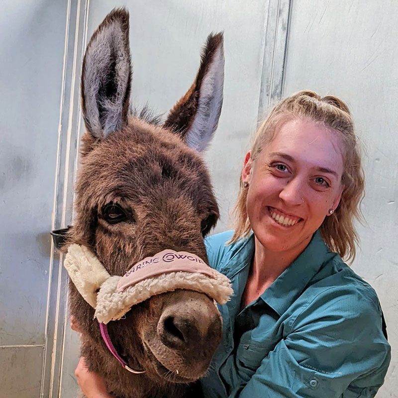 Dr. Andee Frei poses for a portrait with a cute little burro.