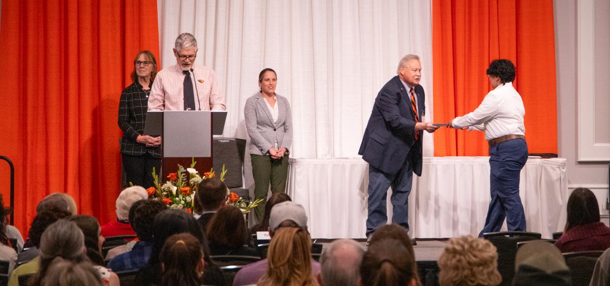 Dr. Bellinghausen hands out an award to a student on a stage