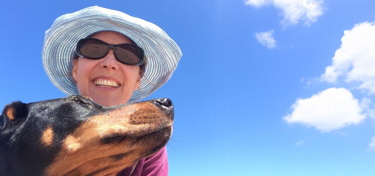Woman and dog selfie with blue sky behind them. 