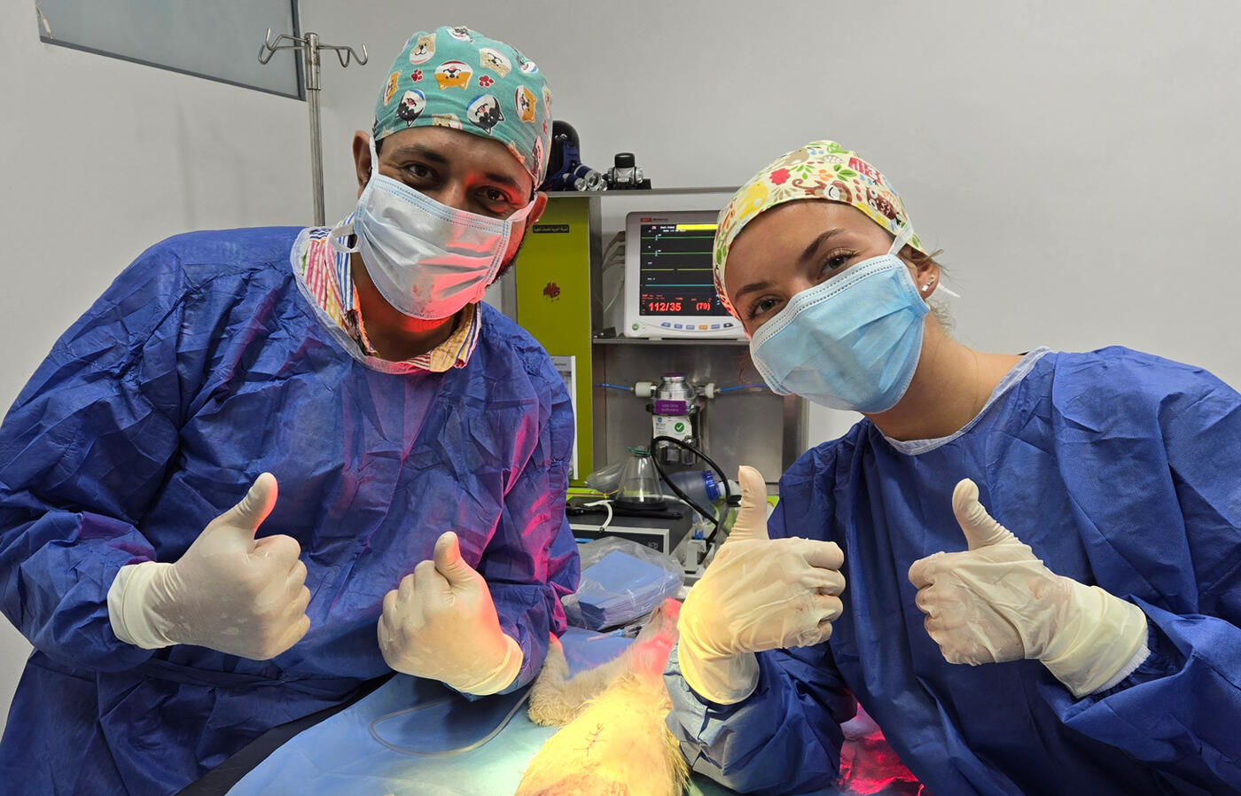 Veterinarian and vet student give thumbs up after a surgery.