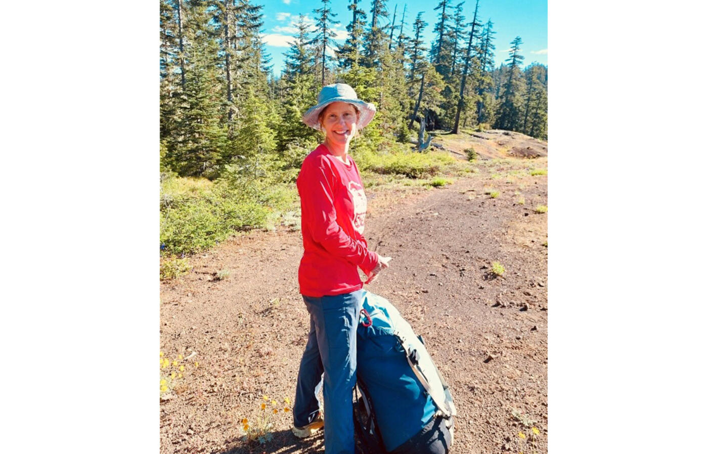 Woman with backpack on trail in the forest.