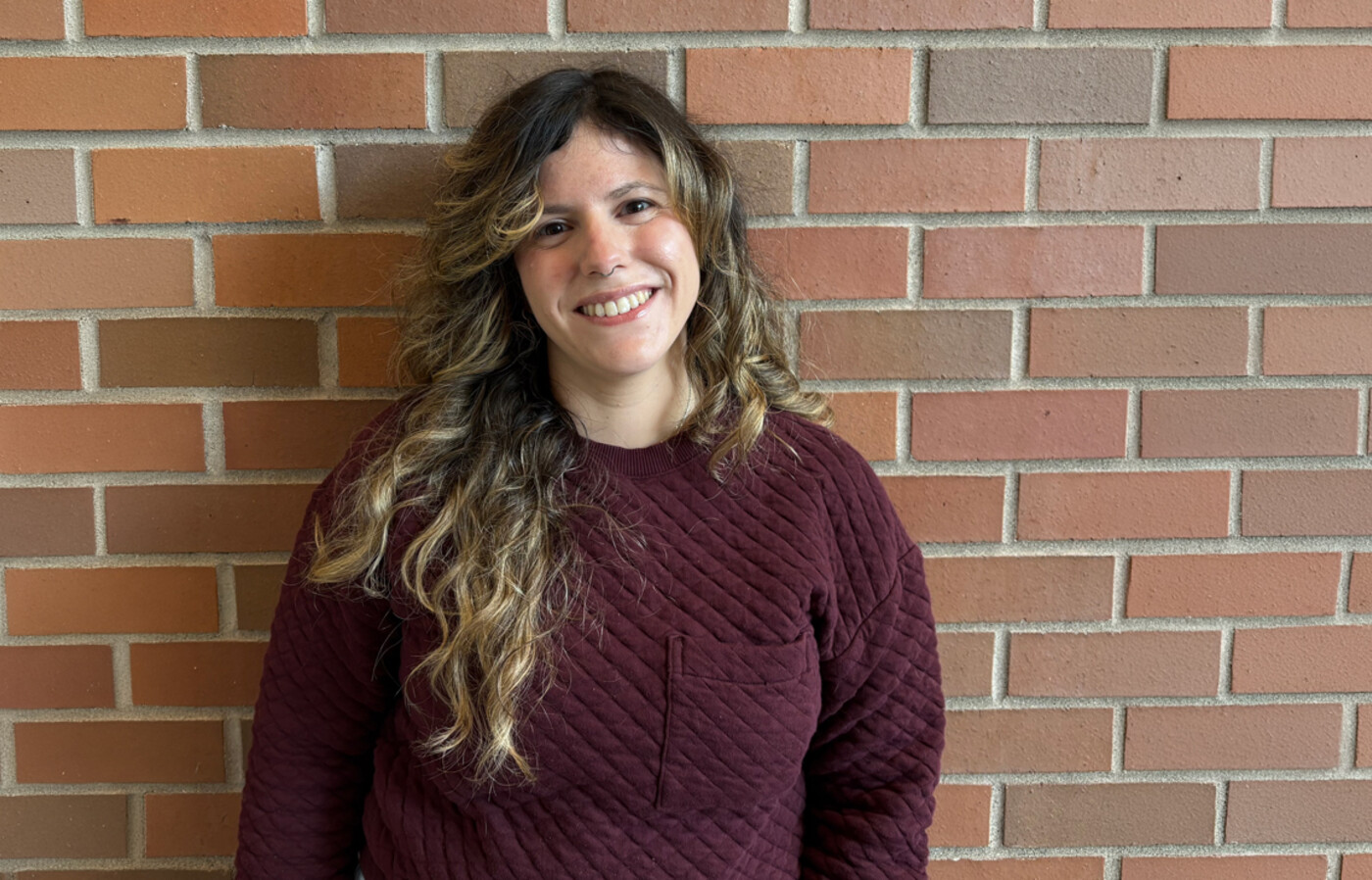 Dr. Tesas stands in front of brick wall.