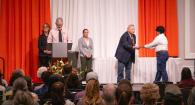 Dr. Bellinghausen hands out an award to a student on a stage