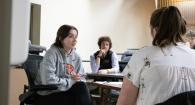 Two people talk in a classroom while another observes.
