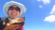 Woman and dog selfie with blue sky behind them. 