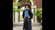 Dr. Patrick Callagy in full doctoral regalia stands in front of archway of Weatherford Hall.