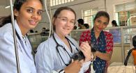 Three people work with a cat on a surgical table