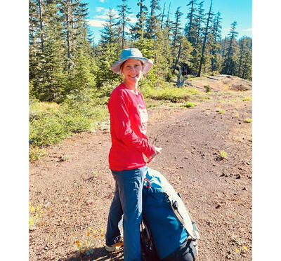 Woman with backpack on trail in the forest.