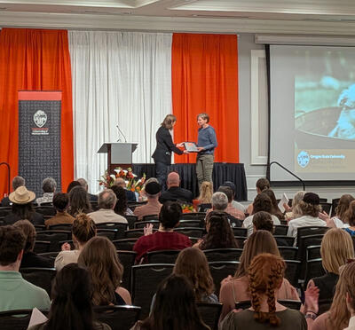 Person receives award from another person on stage. 