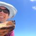 Woman and dog selfie with blue sky behind them. 