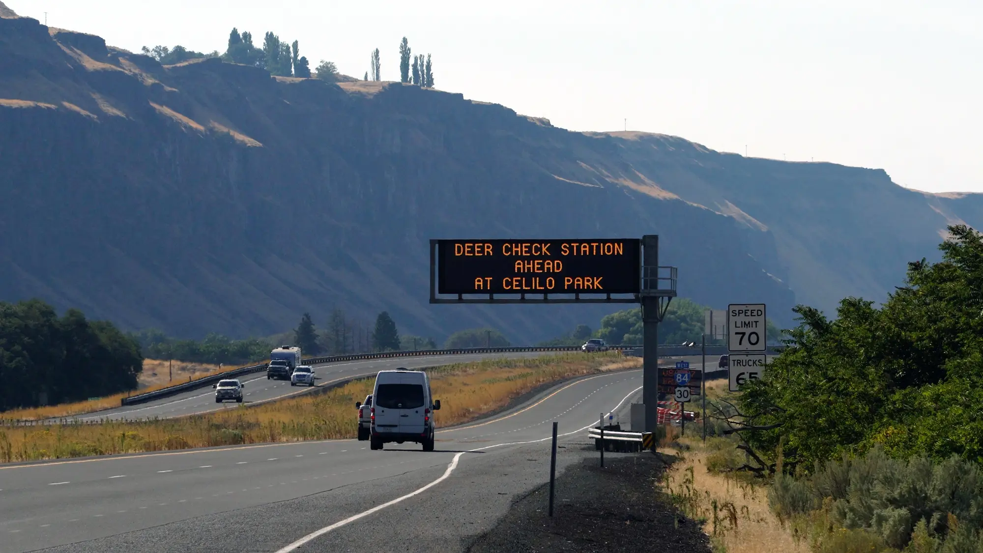 Electronic road sign above I-84 with words: Deer Check Station Ahead at Celilo Park.