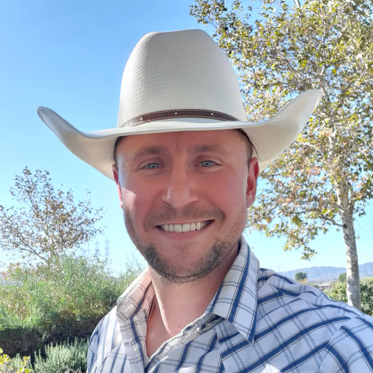 Man in cowboy hat and western shirt outside.