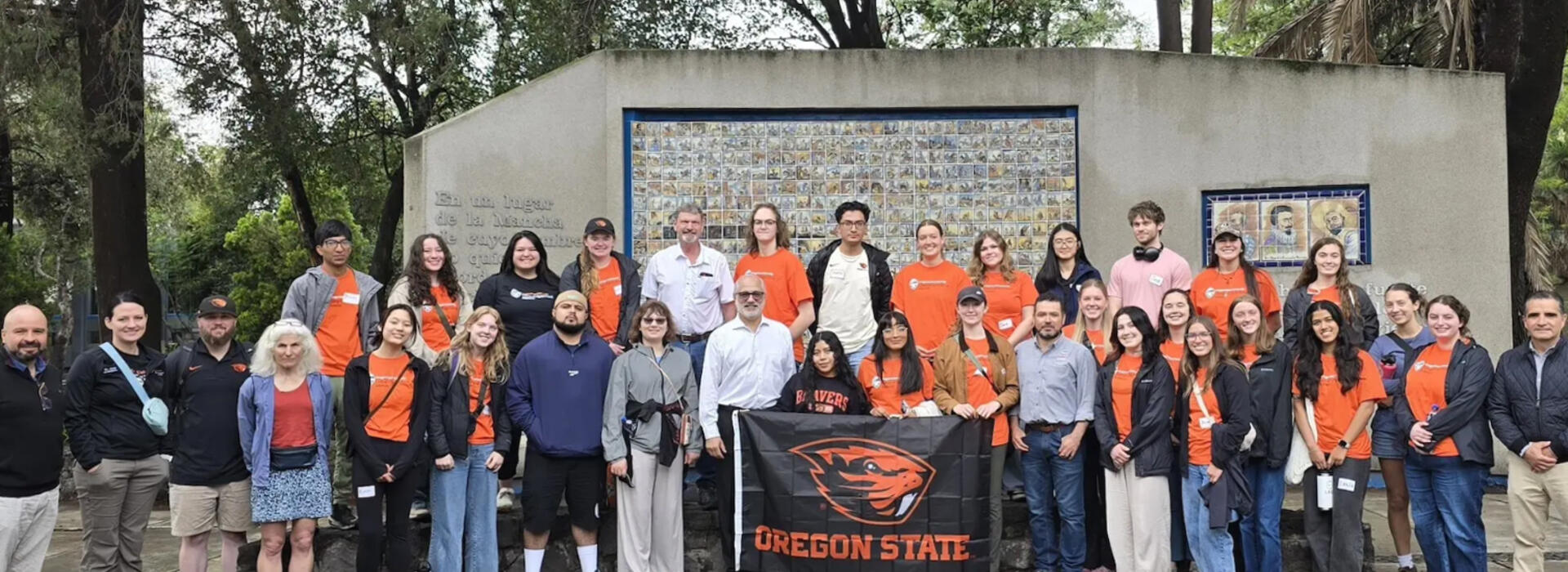 Group of people hold up Oregon State University flag with Beaver logo.