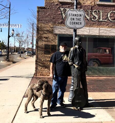 Brown dog standing outside with owner near a statue on the sidewalk