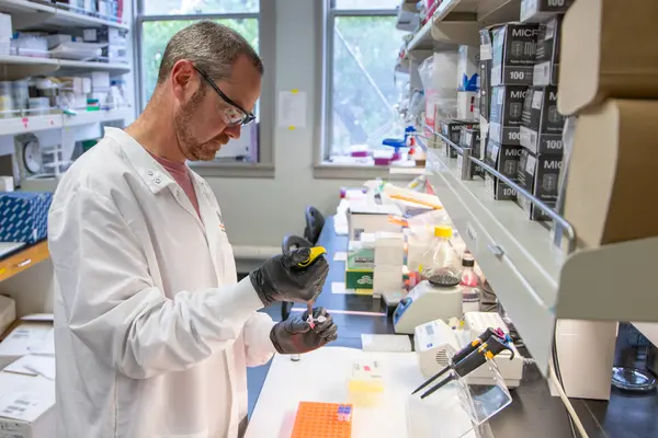 Brian Dolan holds pipette in lab. 