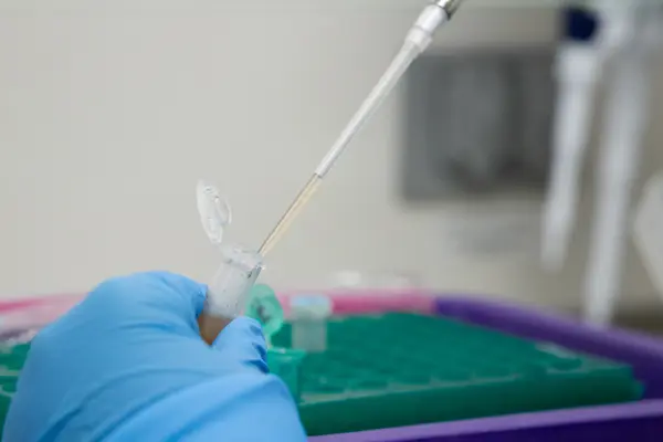 Pipette pulls up a solution from a vial in a laboratory.