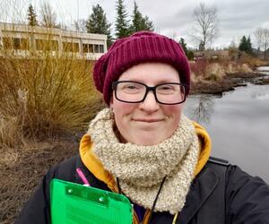 Smiling woman with glasses standing outside