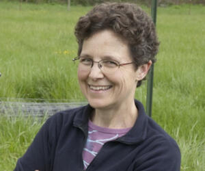 Smiling woman with glasses in a field of grass