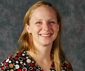 Woman smiling in front of gray background