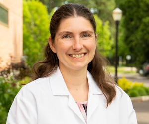 Woman smiling outdoors in a white coat