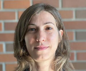 Portrait of Sara Minerva with brick background.