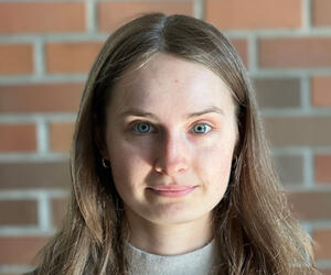 Portrait of person with brick background.