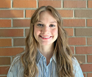 Elizabeth Berry smiling with brick background.