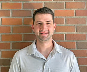 Nathan smiling with brick background.