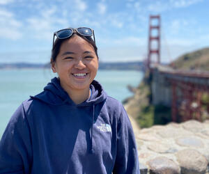 Woman smiles at camera with Golden Gate Bridge in background.