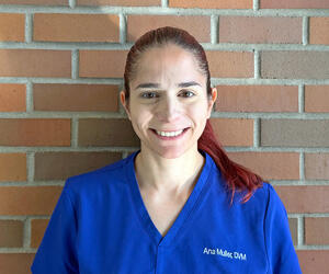 Ana Muller in scrubs with brick background. 