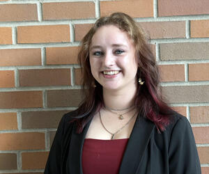 Person stands in front of brick background.