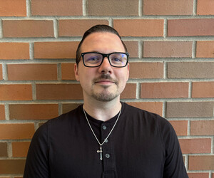 Portrait of person with brick background.